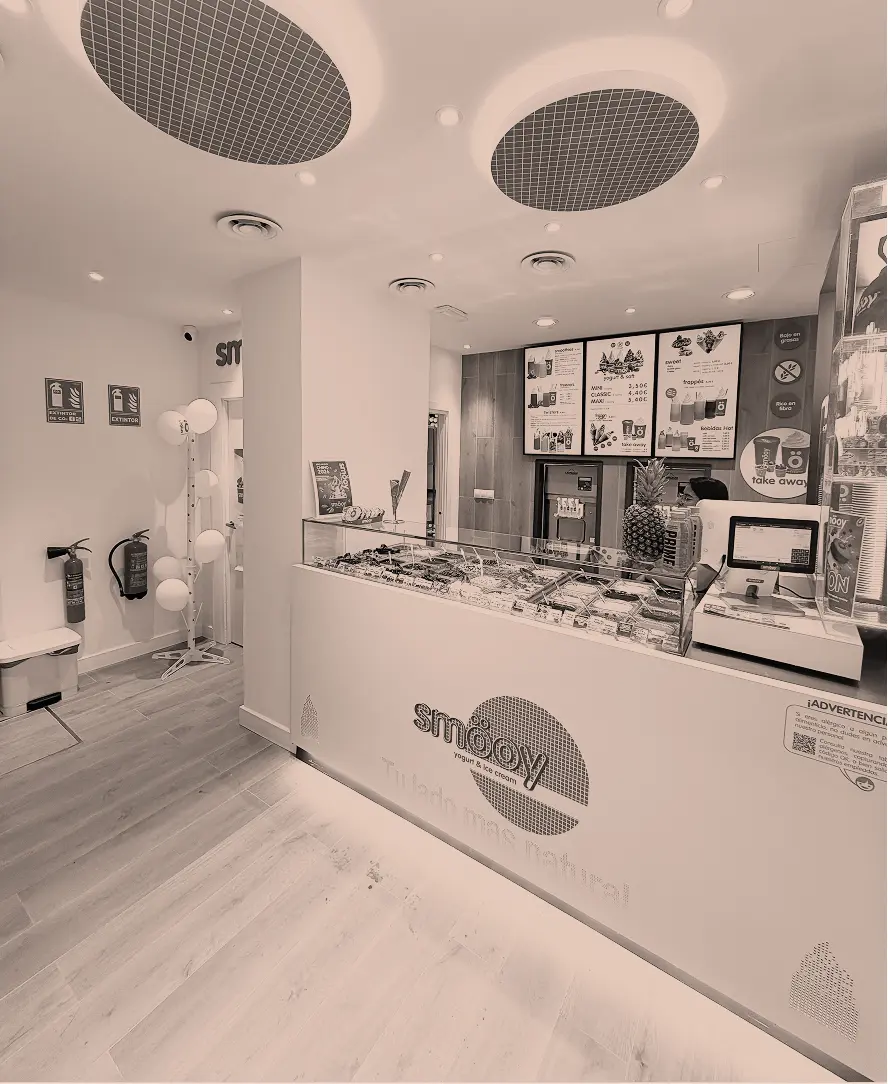 Mostrador moderno de heladería con vitrina refrigerada que exhibe distintos sabores de helado.